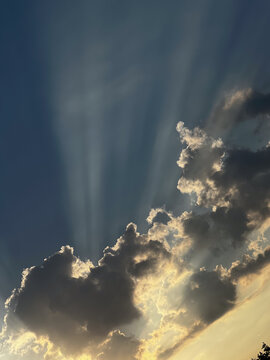 Sunbeams piercing dark clouds in the evening sky