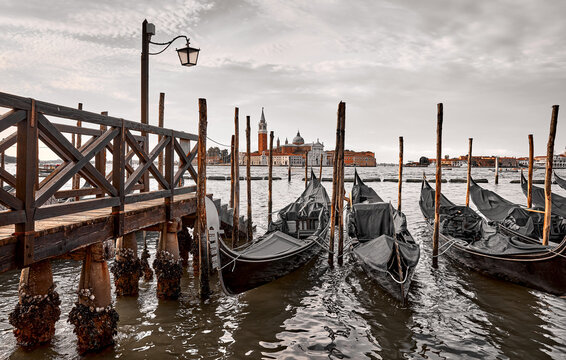 Gondolas near dock in Venice Italy with view to San Giorgio Maggiore skyline picturesque evening sunset landscape panorama..