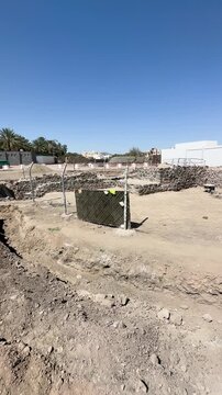 Ancient stone ruins at an archaeological excavation site near modern city buildings.