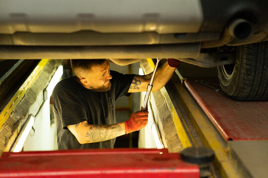 Mechanic with tattooed arm working under car