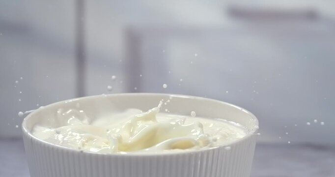 Blueberries falling into a bowl of milk with splash in super slow motion