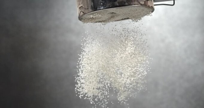 Flour sifts through a sieve creating soft powder cloud in slow motion