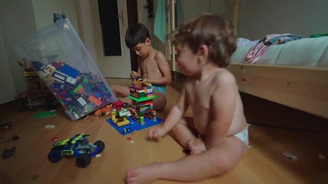 Toddler throwing toys toward older sibling in bedroom at home provocative behavior expressing boundary testing, attention seeking and growing family tension
