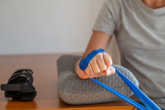 Person performing wrist flexion exercises with a resistance band, strengthening muscles in the forearm and hand to alleviate tendinitis, carpal tunnel syndrome, and repetitive strain injury