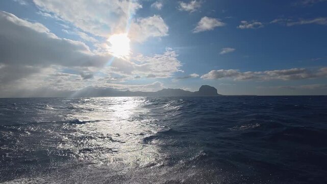 Scenic view of the ocean with Le Morne Brabant mountain in the background under a sunny sky in Mauritius