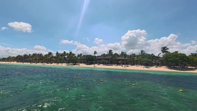 Tropical beach resort with palm trees and turquoise ocean water on a sunny day