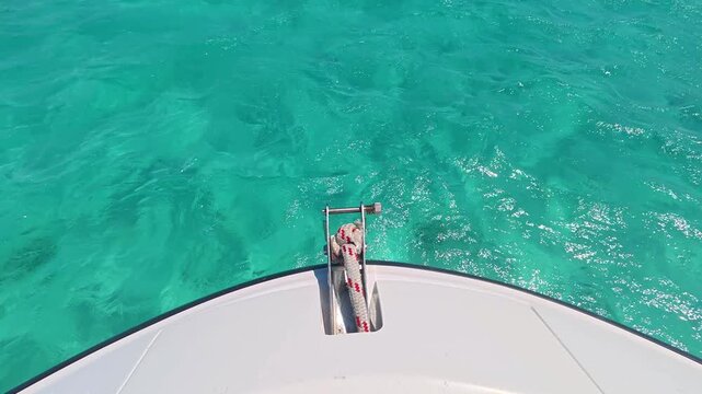 Bow of a boat moving over crystal clear turquoise tropical ocean water