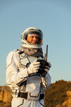 Mars exploration mission with astronaut using communication device in rocky landscape
