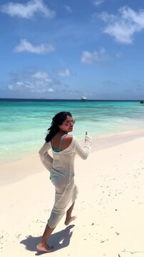 Young woman running on Klein Cura&ccedil;ao tropical beach looking at camera