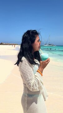 Woman enjoying a cocktail on a tropical beach in Curacao