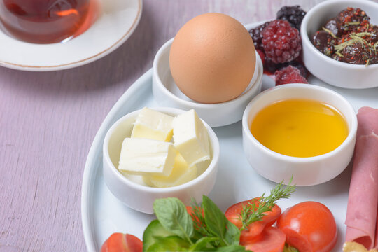 Close-Up View of Boiled Egg, Butter, Honey, and Fresh Ingredients on Breakfast Platter