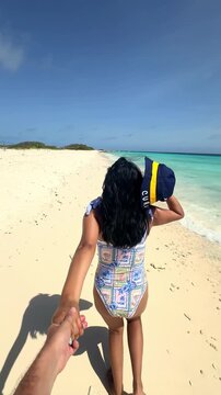Woman leading her boyfriend on a tropical beach in Cura&ccedil;ao