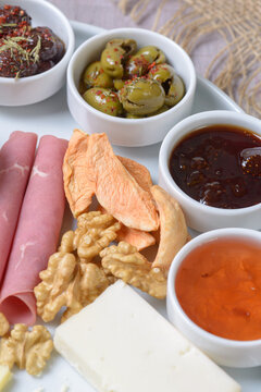 Close-Up View of Seasoned Olives, Jams, Walnuts, Dried Apples, and Cheese on Breakfast Platter