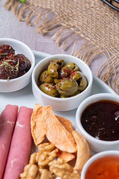 Close-Up View of Seasoned Olives, Jams, Dried Apples, and Walnuts on Breakfast Platter