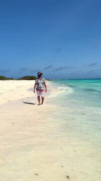 Carefree man walking on tropical Caribbean beach in Klein Cura&ccedil;ao
