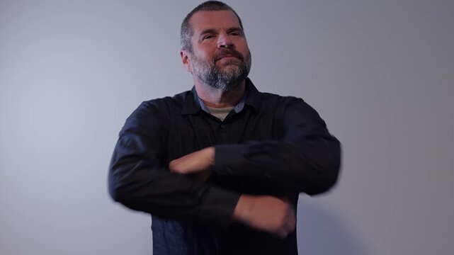 Confident middle-aged man with beard wearing a dark button-down shirt posing against a neutral backdrop, representing modern business leadership