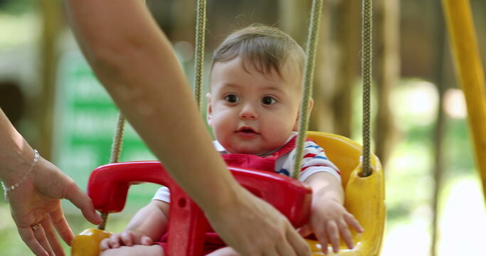 Cute adorable baby boy at park swing outdoors mom pushing infant son at playground swing