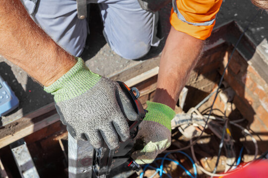 Engineer lifting fibre distribution point on hinged arm in street chamber