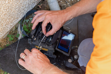 Telecoms engineer slides plastic shrink wrap over fused bare fibre strands © Tosh Lubek