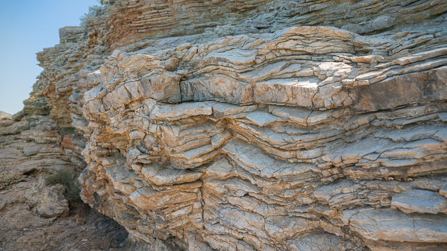 Layered rock formation and coastal cliff texture under natural sunlight on a bright summer day