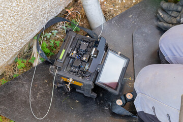 Overhead view of open fusion splicer with fibre loaded on work mat at residential exterior © Tosh Lubek