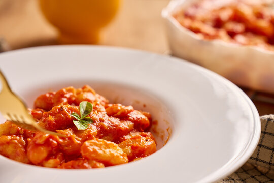 Gnocchi in tomato sauce served on plate with basil garnish and fork