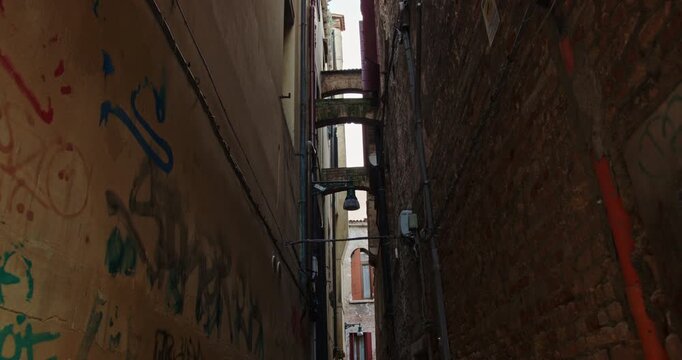Walking down a narrow venetian alley with graffiti