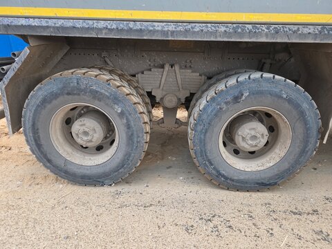 Dual Rear Wheels on Heavy Dump Truck Close-up of dual rear wheels, tandem axles, and leaf spring suspension on a dusty heavy-duty dump truck at a worksite