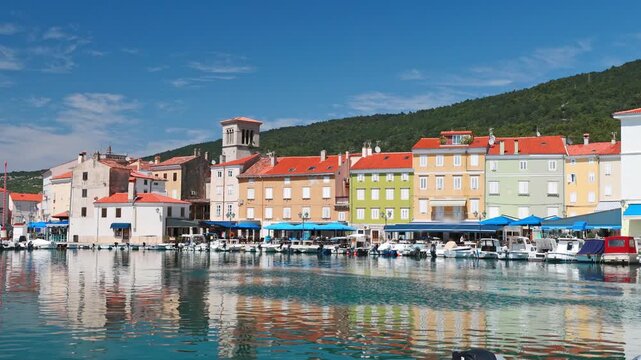 Cres town square, Trg Frane Petrica, presenting historic Venetian architecture reflected in a central fountain under a blue summer sky, featuring street cafes and clock tower in Cres Island of Croatia