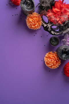 Decorative mask with marigold and candle for Dia de los Muertos altar celebration in Mexico on vertical violet backdrop