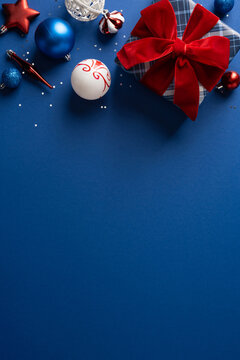 Christmas and New Year gift with red velvet bow and blue ornaments on festive vertical background