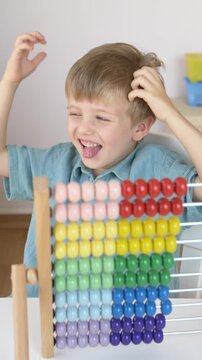 Boy making funny faces and laughing instead of studying during home learning activity. Natural childhood behavior, emotional expression, playful personality and authentic family life concept. 
