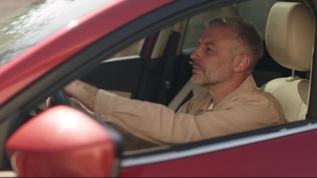 Focused man driving car, viewed through side window, hand on wheel, 4K