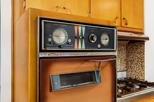 A vintage Caloric Ultramatic wall oven from the 1950-1960's surrounded by wooden cabinets. The company was acquired multiple times before going out of business.