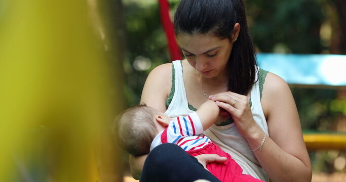 Candid mother holding baby infant boy outside at park