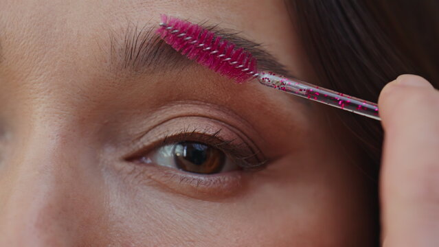 Beautiful woman brushing eyebrows with cosmetic spoolie home closeup. Young lady