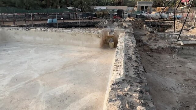  Stone pool and active archaeological excavation site near a palm oasis.