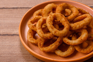 Naklejka premium Deep fried breaded onion or squid rings, crispy fast food snacks. Fried onion or squid rings