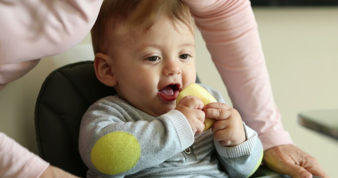 Casual candid family scene of parent putting meal table for baby to eat