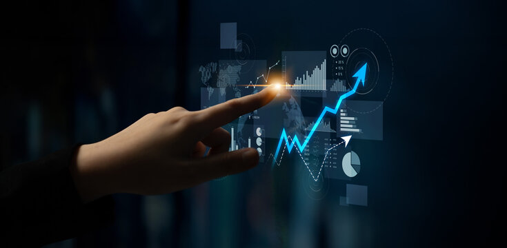 A close-up view of a hand interacting with a futuristic digital interface displaying graphs and charts, symbolizing business growth, analytics, and data-driven decision making. Scalp