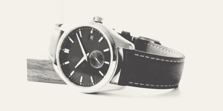 Elegant silver wristwatch with black leather strap on a minimalist wooden stand with soft studio lighting