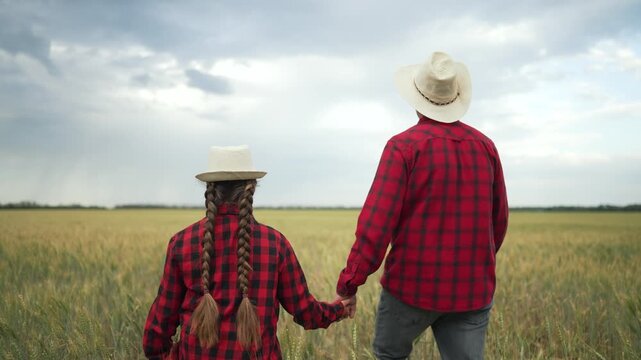 Father and daughter in field. Family walks together in nature. Red plaid shirts straw hats holding hands. Rural family lifestyle concept. Family enjoying nature together in field. Family love in field