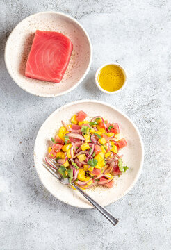 Gourmet tuna mango salad tartar with cilantro and purple onion on white plate
