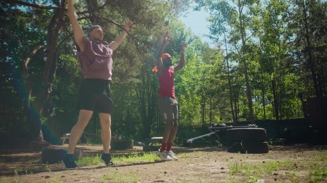 Caucasian young adult man and African American young adult man doing jumping jacks during outdoor workout in slow motion. Footage ideal for diversity in fitness and wellness marketing