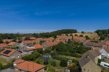 Obraz premium Aerial view over the residential neighbourhood of Pickering North Yorkshire showing detached houses gardens surrounding countryside rolling fields and woodland beneath a clear blue summer sky