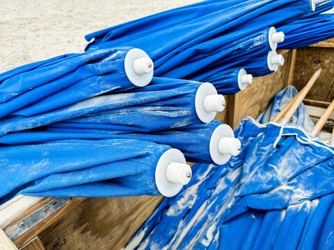 Folded blue beach umbrellas with sand on folly field road, South Carolina