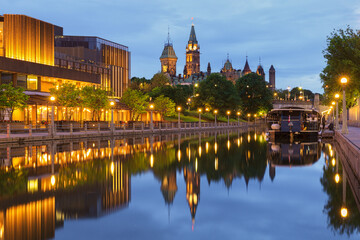 Obraz premium Evening view of the Rideau Canal in downtown Ottawa, Canada, with illuminated waterfront buildings, city lights and colorful reflections on the calm water