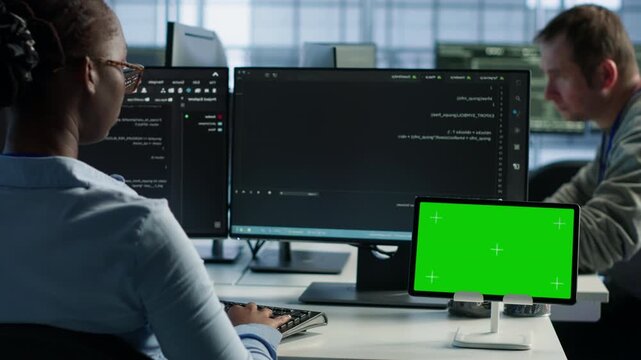 Data center isolated screen tablet in front of IT support workers coding on computers while combining power management, hardware monitoring and server room operations.