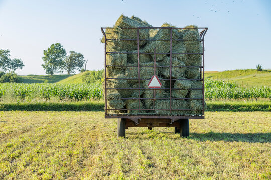 A full hay wagon with a slow-moving vehicle sign on the back.