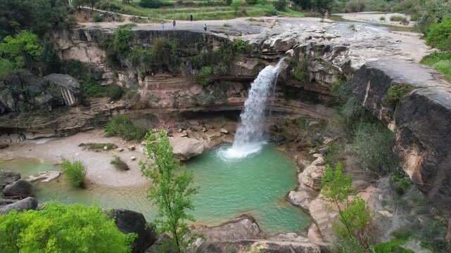 Forward reveal aerial shot of Salto de La Portellada waterfall on cloudy spring day. Teruel, Aragon, Spain.